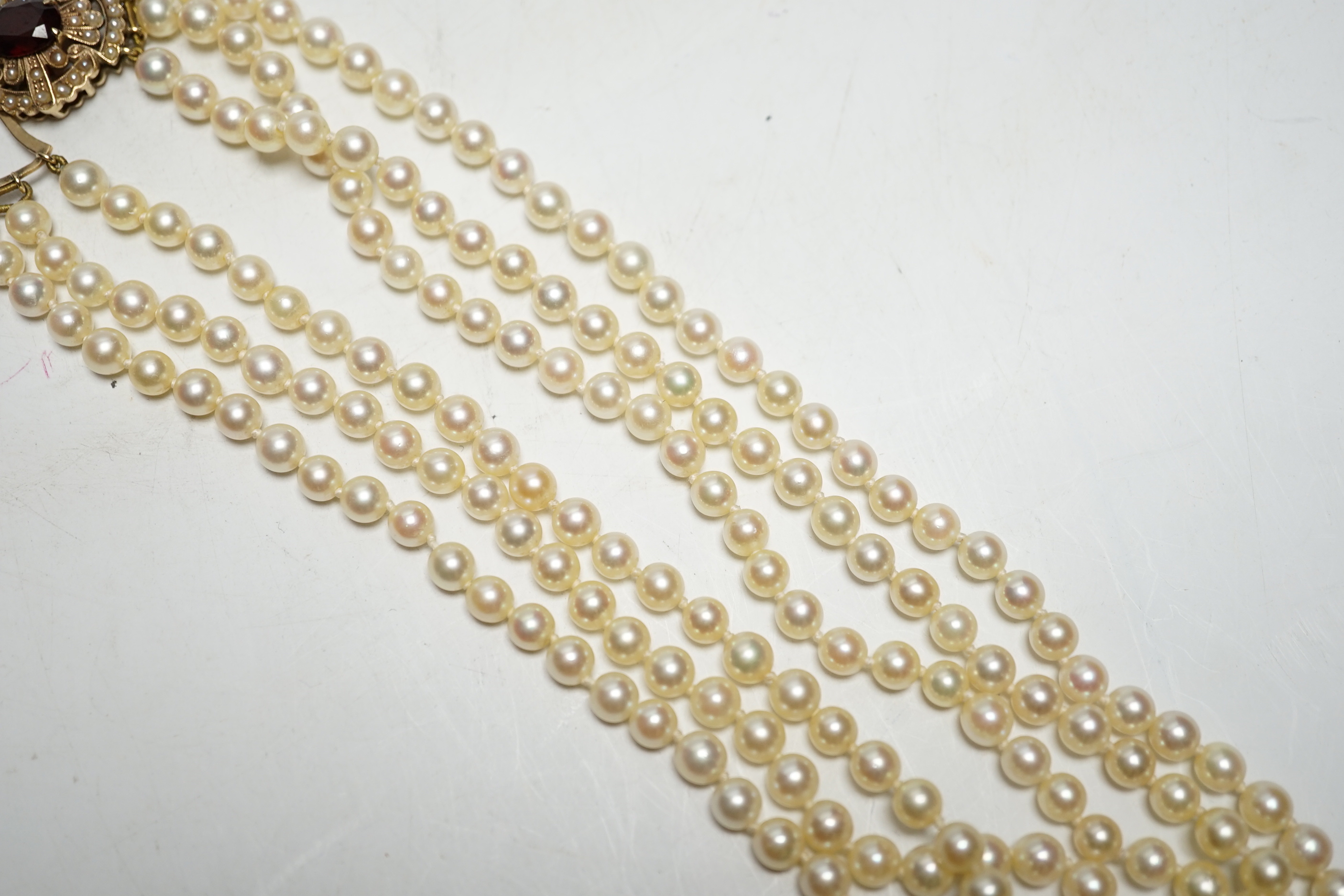 A 1960's triple strand cultured pearl necklace, by Cropp & Farr, with 9ct gold, garnet and seed pearl set clasp, 40cm.